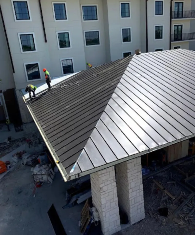 Crew installing standing seam metal roof panels on a commercial project in Lincolnia